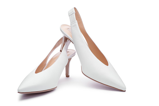 A pair of white women's leather open-back high-heeled shoes isolated on the white background. Close up view. Fashionable stylish feminine shoes, shoes for bride