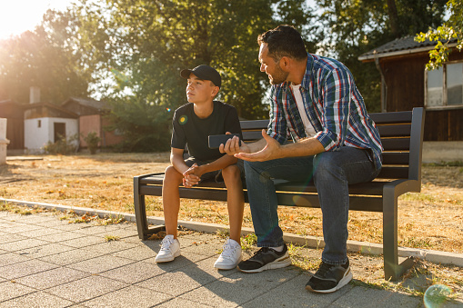 Meaningful conversation, father and son sharing a moment on a park bench,