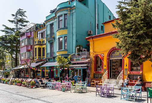 Tourists enjoying a sunny afternoon, sitting at outside cafes and restaurants on this colorful street in the Sultanahmet district, Istanbul, Turkey