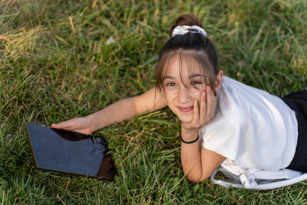 istock Kids girls using tablet in greenery field. 1517973904