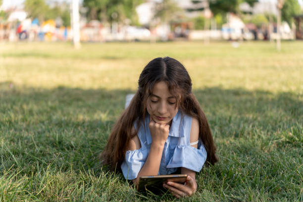 istock Kids girls using tablet in greenery field. 1517975384