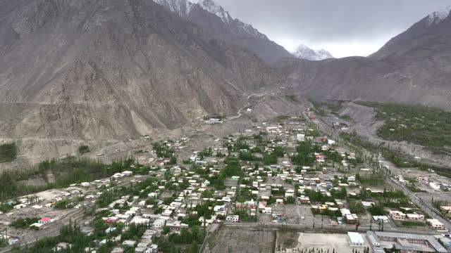 Scenic aerial view drone view flying over Skardu Central Mosque and Skardu city Surrounding with Snow Cap Mountain in Skardu, Northern Pakistan