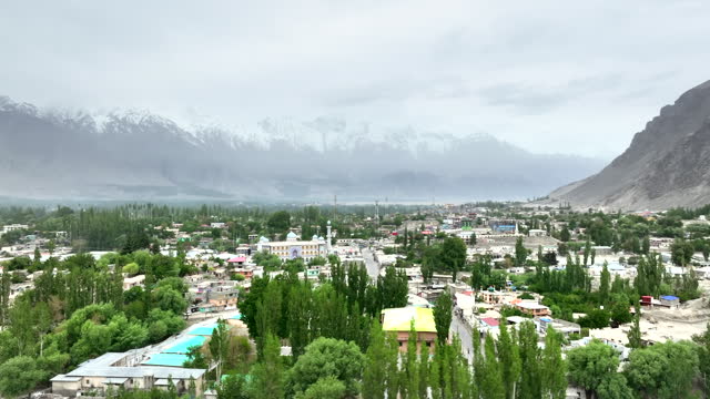 Scenic aerial view drone view flying over Skardu Central Mosque and Skardu city Surrounding with Snow Cap Mountain in Skardu, Northern Pakistan