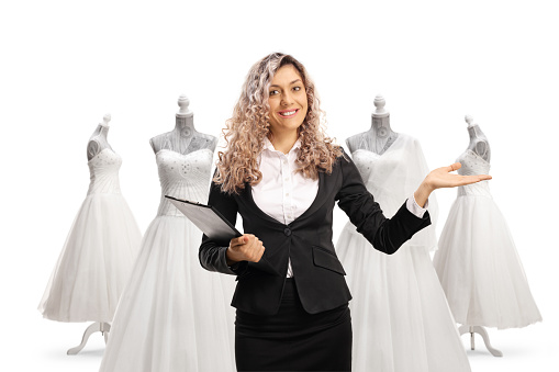 Businesswoman holding documents and gesturing welcome at a bridal shop isolated on white background