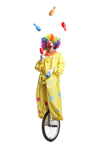 Clown on a unicycle juggling isolated on white background