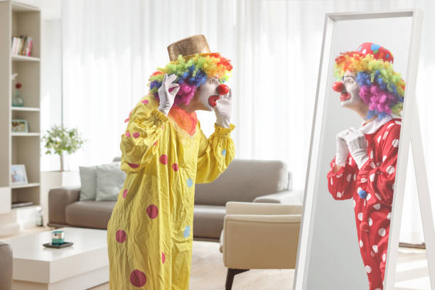 Clown looking at another clowin in a mirror reflection inside a room