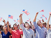 Smiling people waving American flags and looking up in crowd