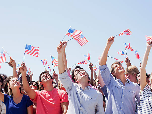 uśmiech ludzie machający amerykańskie flagi i patrzeć w górę w tłum - flag fourth of july one person patriotism zdjęcia i obrazy z banku zdjęć