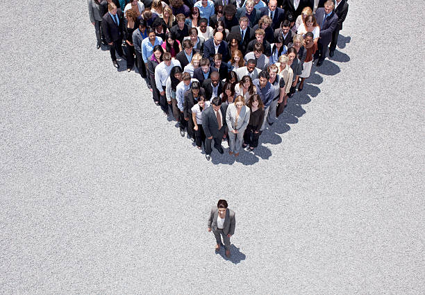 Businesswoman at apex of crowd  standing out from the crowd stock pictures, royalty-free photos & images