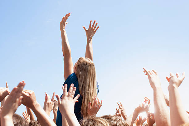 Woman with arms raised above crowd  cheering stock pictures, royalty-free photos & images