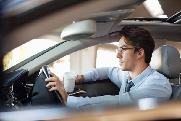 empresario sosteniendo una taza de café y de conducción de coche - conductor oficio fotografías e imágenes de stock