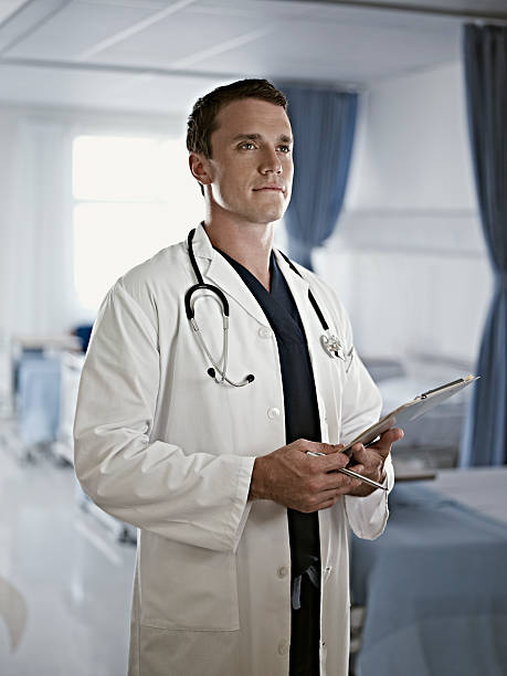 portrait of confident doctor holding medical record in hospital room - üç dönem uzunluğu stok fotoğraflar ve resimler