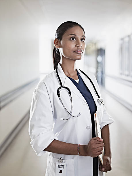 Portrait of pensive doctor holding medical record in hospital corridor  three quarter length photos stock pictures, royalty-free photos & images