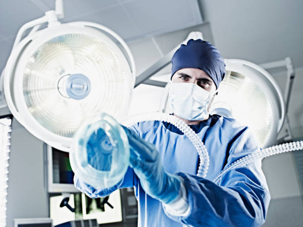 Portrait of surgeon holding oxygen mask under surgical lights  surgical light stock pictures, royalty-free photos & images