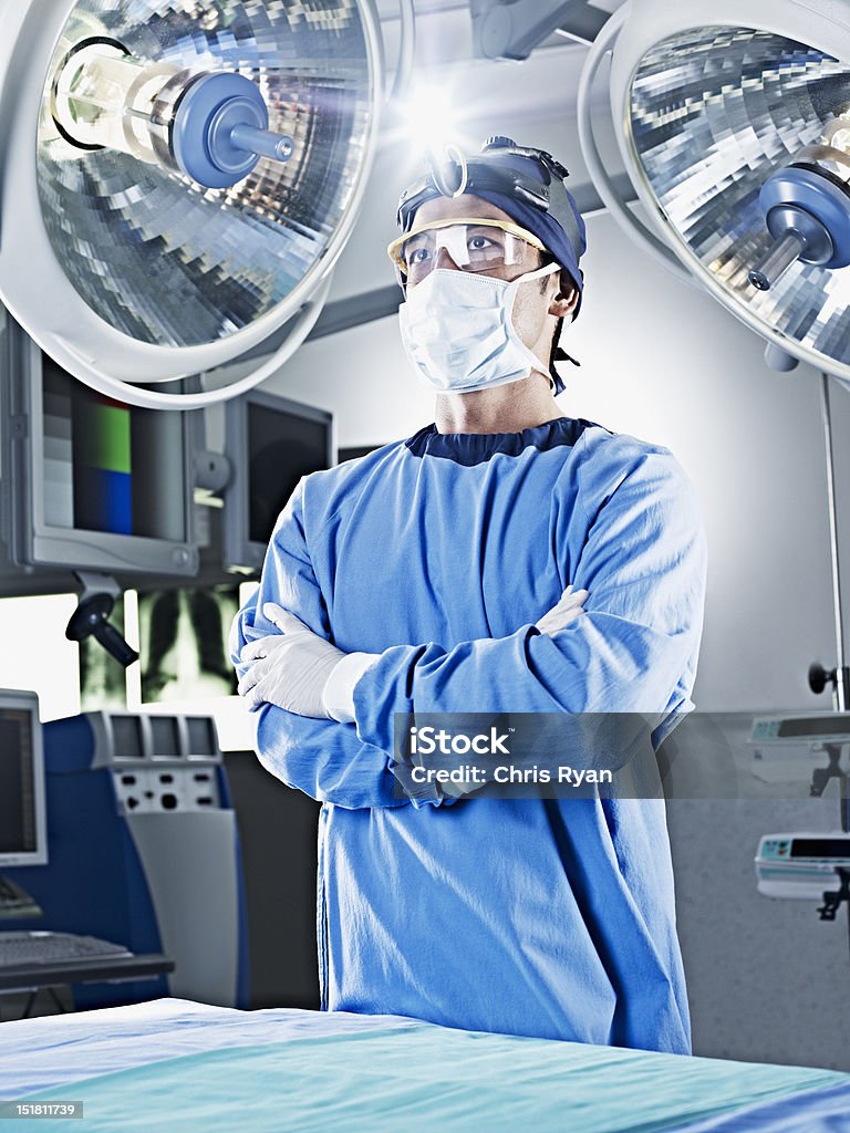 Portrait of serious surgeon with arms crossed under surgical lights  Operating Room Stock Photo