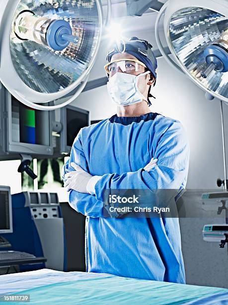 Portrait Of Serious Surgeon With Arms Crossed Under Surgical Lights Stock Photo - Download Image Now