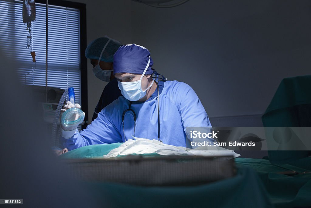 Cirurgião com máscara de oxigênio com paciente em Sala de cirurgia - Foto de stock de Doutor royalty-free