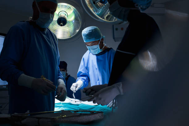 surgeons working in operating room - ห้องผ่าตัด โรงพยาบาล ภาพสต็อก ภาพถ่ายและรูปภาพปลอดค่าลิขสิทธิ์
