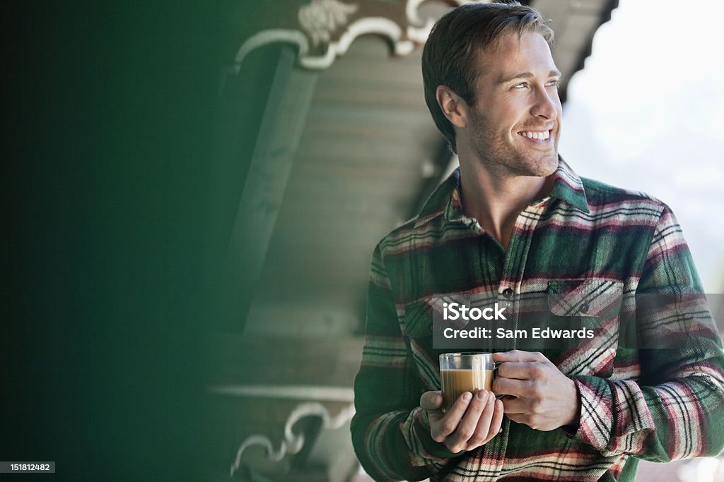 Uśmiech człowiek pije kawę na pokładzie Weranda - Zbiór zdjęć royalty-free (Zima)