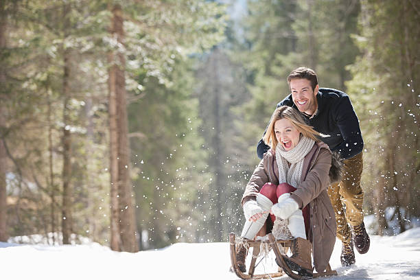 donna per uomo di spingere slitta sulla neve woods - active holidays foto e immagini stock