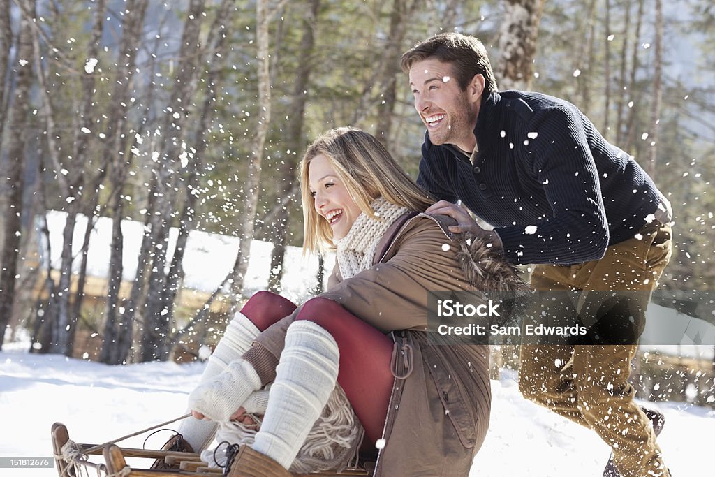 Sonriendo par de paseos en trineo en la nieve - Foto de stock de Invierno libre de derechos