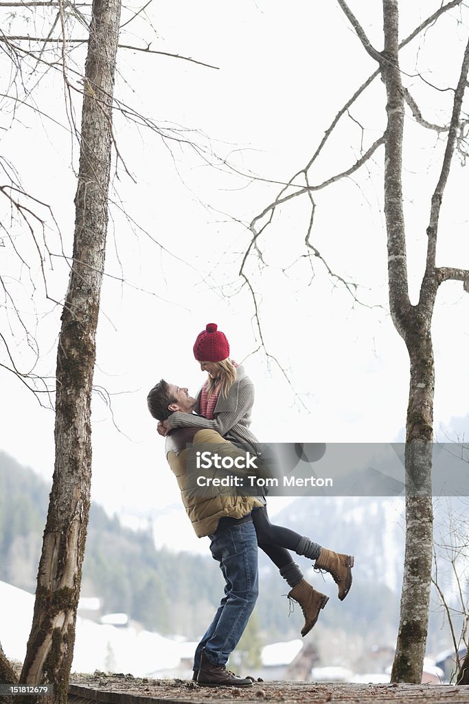 Man lifting woman in snowy woods  Winter Stock Photo