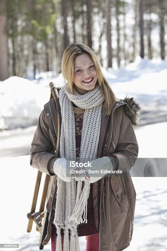 Portrait de femme souriante luge dans la neige bois - Photo de 25-29 ans libre de droits