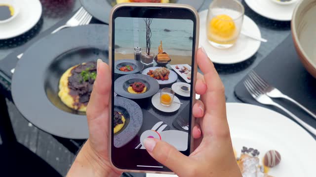 Closeup of a woman's hands using smartphone to take photos of dinner