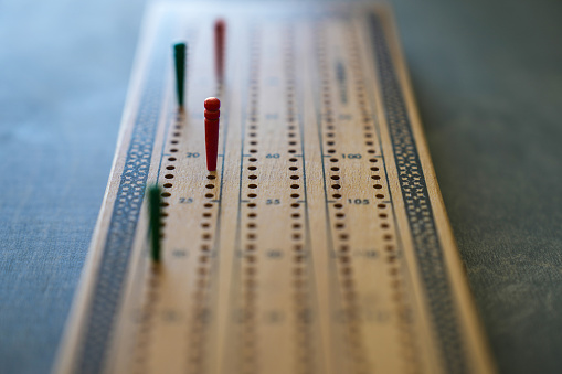 Close up focus of red and green pegs on a wooden cribbage board
