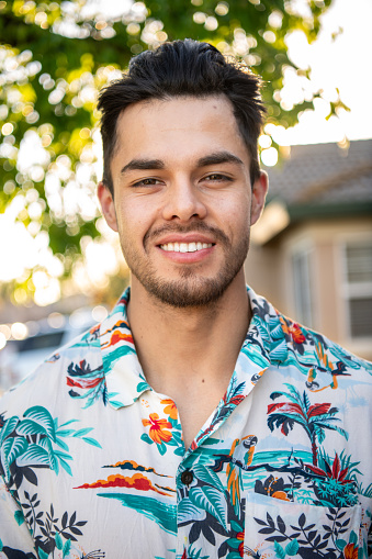 Smiling Young hispanic man looking at the camera at his home front yard