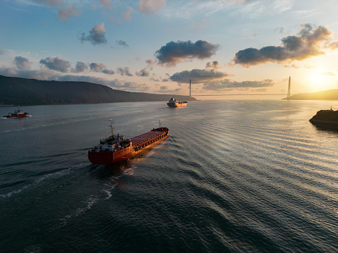 Aerial view of two cargo ship passing through Istanbul Bosphorus for import and export business logistic at sunrise.