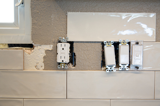 White subway tile backsplash installation for a home renovation project. Electrical switchplates.