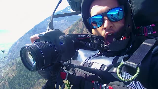 man photographer enjoying paragliding adventure at mountains at day