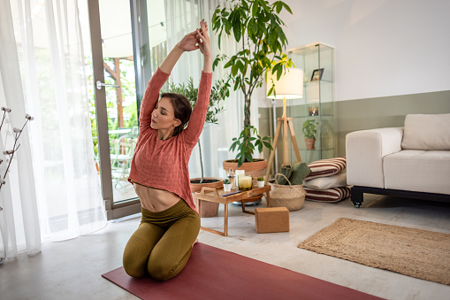 Photo of a young woman practicing yoga and meditation at home.