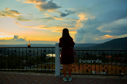 Silhouette of woman watching scenery during sunset over the mountain with dramatic sky