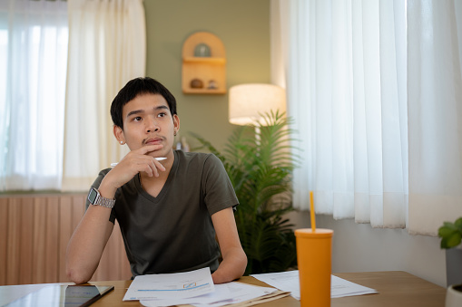 Young Asian disability man working on digital tablet analyzing business strategies at home.