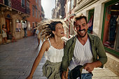 Playful couple having fun while running on the street.