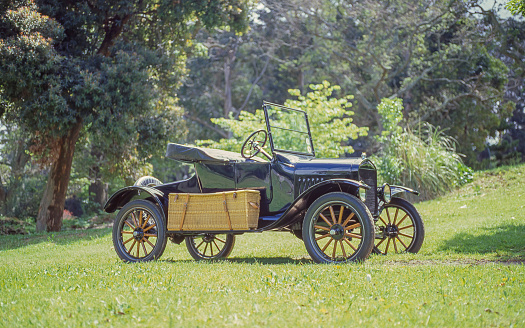 Young man learning to drive a circa 1915 roadster car in a farm field in 1918.