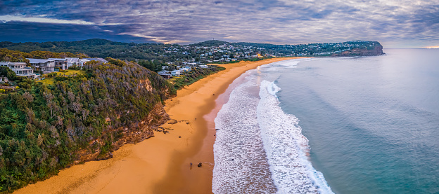 Aerial sunrise with cloud filled sky and small waves at Macmasters Beach on the Central Coast, NSW, Australia.