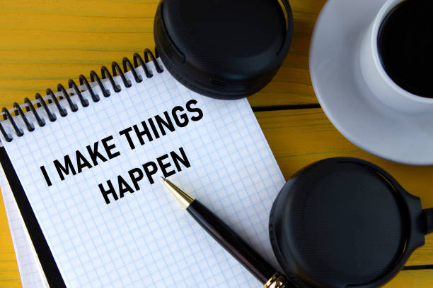 istock I MAKE THINGS HAPPEN - words on a white notepad on a yellow background with headphones, a cup of coffee and a pen 1518614273