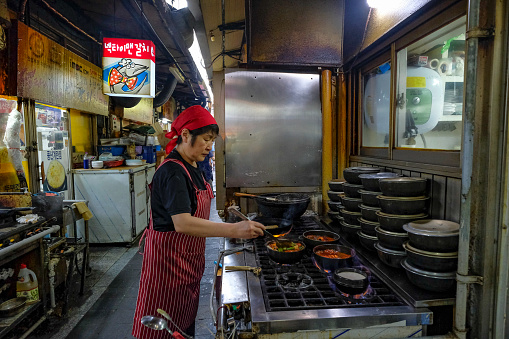 Seoul, South Korea - July 6, 2023: A woman preparing food at the Namdaemun Market in Seoul, is the oldest market in South Korea..