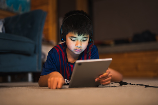 Child wearing microphone listening to music using digital tablet.