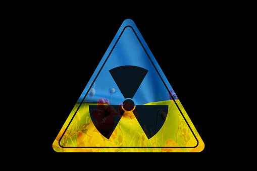 Radiation sign black and yellow and the flag of Ukraine and poppy flowers on a black background, danger and radiation, a warning sign about radiation in Ukraine