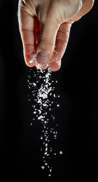 istock Male hand sprinkling edible salt at black background. 1518723751
