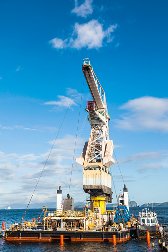 Installation of a large floating crane with the help of sea tugs, on a semi-submersible transport vessel, for its transportation by sea.