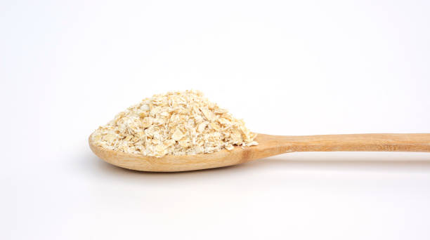 istock Oatmeal in a wooden spoon on a white background. 1518780049