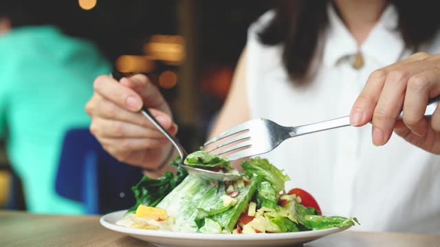 Woman eats vegetarian salad at restaurant.