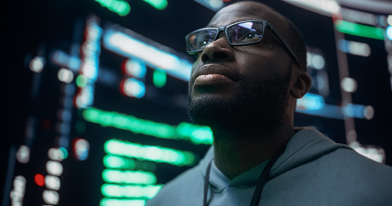 Close-Up Portrait of Young Black Man Looking at Big Digital Screens Glitching While Displaying Code. Worried Professional Programmer Fixing a Bug, Dealing with Crashing System, Thinking of Solutions.