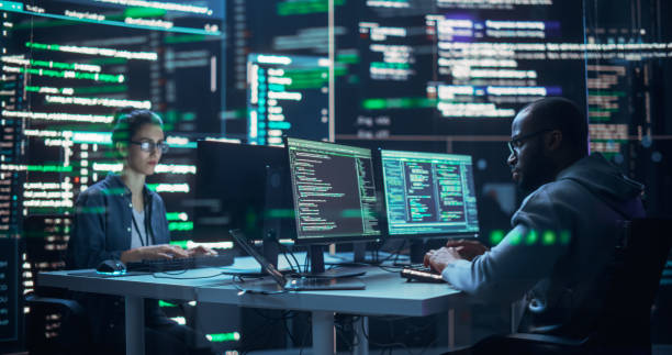 istock Portrait of Two Diverse Developers Working on Computers, Typing Lines of Code that Appear on Big Screens Surrounding Them. Male and Female Programmers Creating Innovative Software, Fixing Bugs. 1518856355