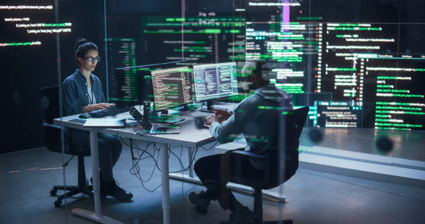 istock Portrait Two Diverse Developpers Working on Computers, Typing Lines of Code that Appear on Big Screens Surrounding Them. Male and Female Programmers Creating Innovative Software, Fixing Bugs 1518856995